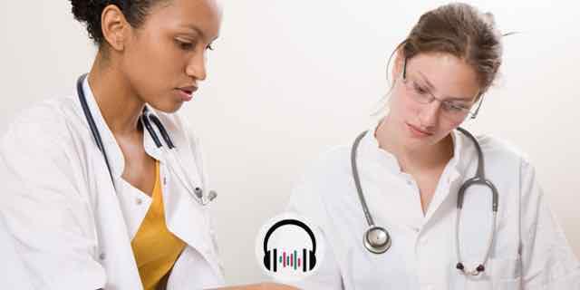 duas medicas olhando para livros e conversando