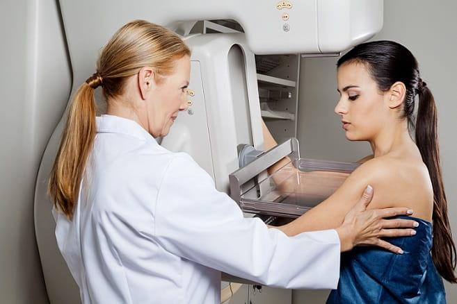 médica assistente realizando mamografia em mulher com suspeita de câncer de mama