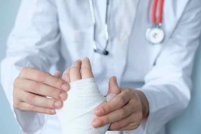 médico enfaixando a mão do paciente