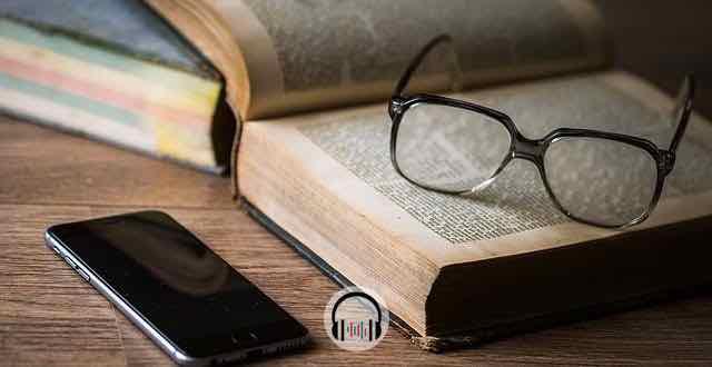 óculos em cima de um livro com um celular do lado