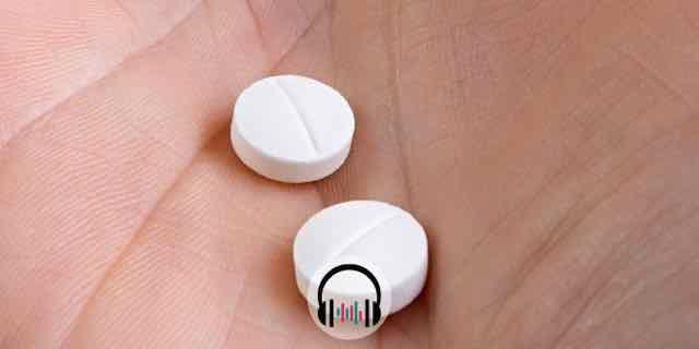 mão segurando duas aspirinas