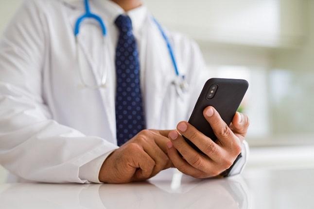 Médico realiza telemedicina pelo celular por causa do isolamento social causado pela pandemia de COVID-19