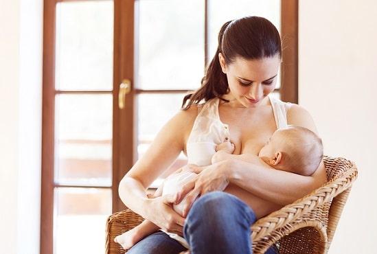 mãe amamentando bebê que faz uso de fórmulas infantis sentada
