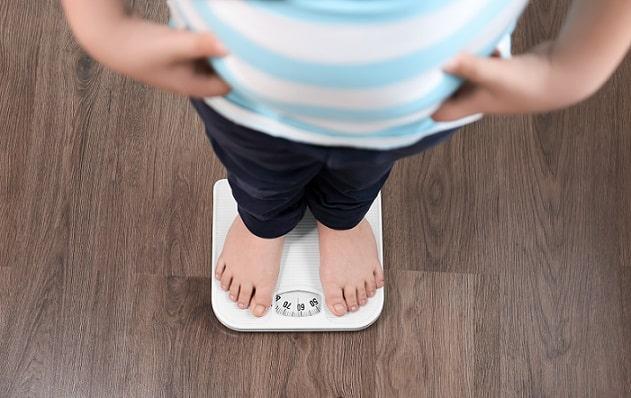 criança com obesidade se pesando
