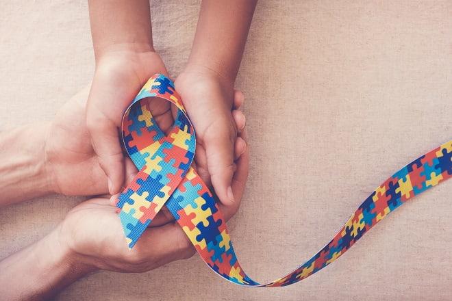 mãos segurando a fita símbolo do Dia Mundial de Conscientização do Autismo