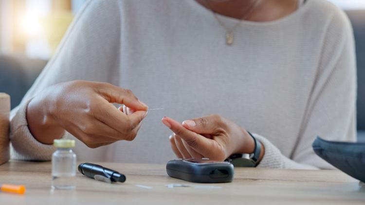 Mãos de mulher negra manipulando aparelho para controle da diabetes tipo 1