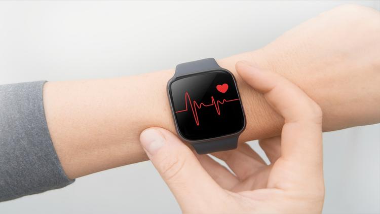 mão de mulher com smartwatch medindo a frequência cardíaca, representando a tecnologia e medicina