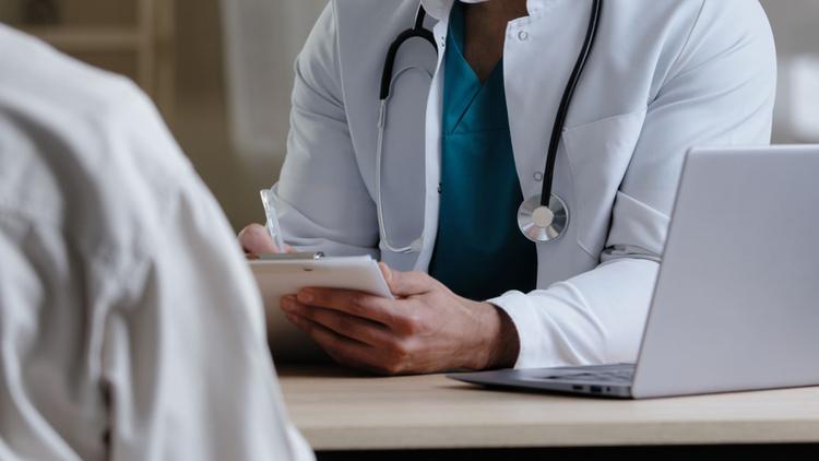 Médico dermatologista atendendo paciente idoso com lesão de pele