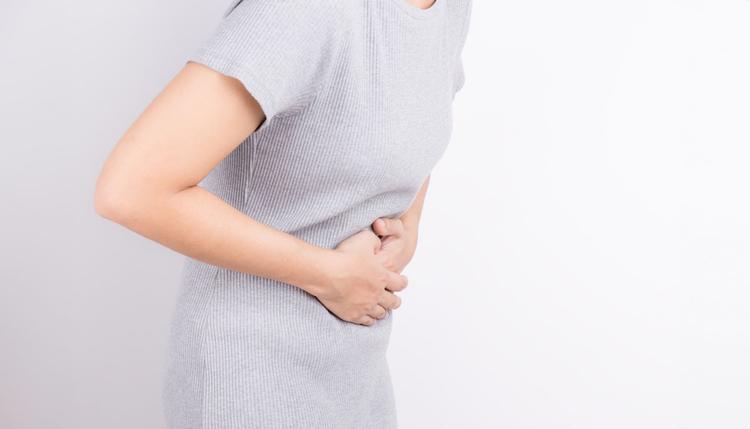 Mulher com abdome agudo levando as mãos à barriga