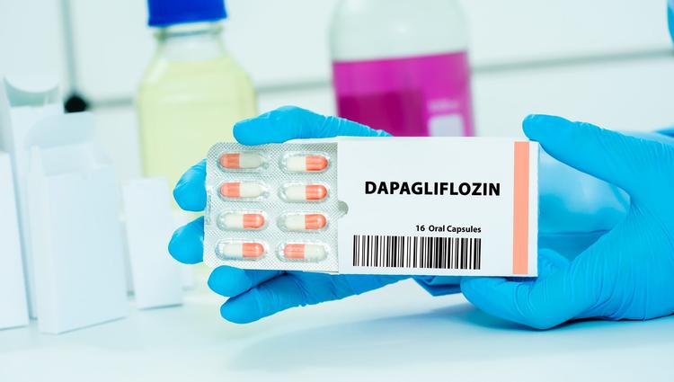 mãos enluvadas segurando a caixa de comprimidos de dapagliflozina